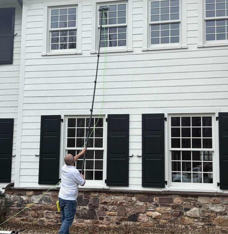 Cleaning windows on a home with black shutters